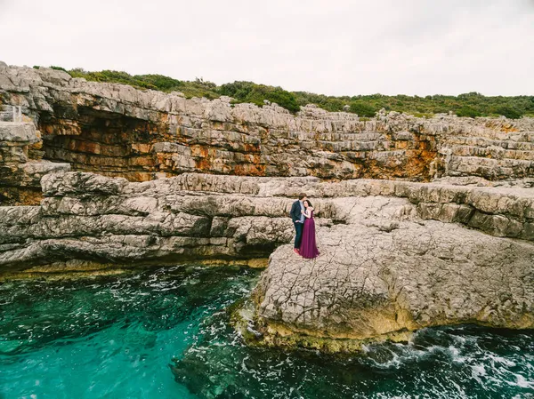 Hombre y mujer abrazándose en las rocas contra el fondo del mar azul hirviente. Vista aérea — Foto de Stock