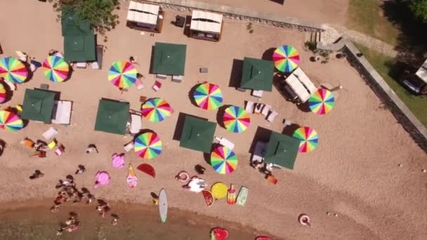 Drone kilátás fényes szivárvány napernyők Queens Beach, a Villa Milocer közelében — Stock videók