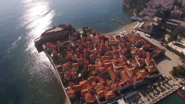 Cidade velha de Budva em uma península com espreguiçadeiras nas praias. Drone. — Vídeo de Stock