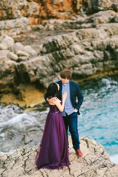 Man knuffelt vrouw terwijl staan op een richel boven de zee tegen een achtergrond van rotsen — Stockfoto