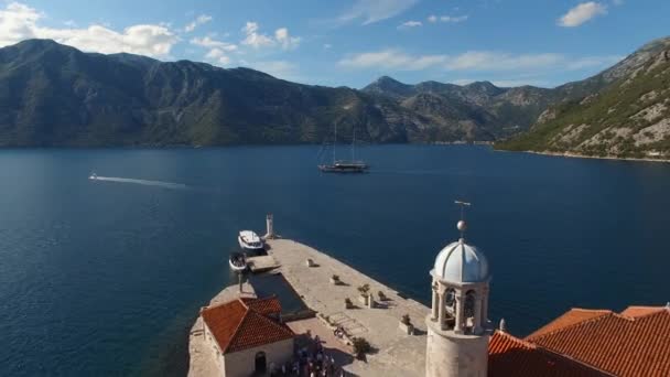 Velero navega a lo largo de la bahía pasando por la isla de Gospa od Skrpjela — Vídeos de Stock