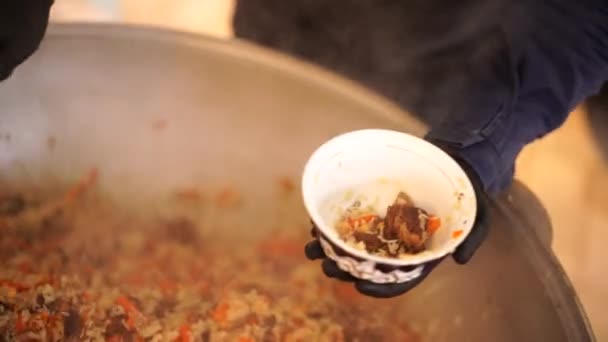 Chef gießt usbekisches Pilaf aus dem Kessel in einen tiefen Teller — Stockvideo