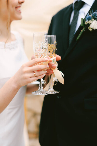 Bride and groom clink glasses of champagne. Close up