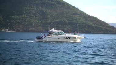 Beyaz yat, dağların arka planına karşı denizde yüzüyor. Perast, Karadağ