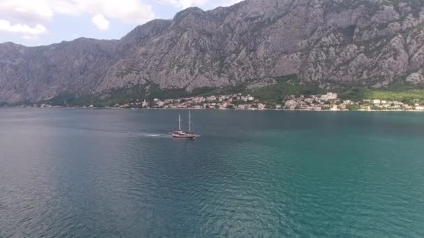 Zeilboot vaart op de Kotor Bay tegen de achtergrond van de bergen en de kust van Prcanj — Stockvideo