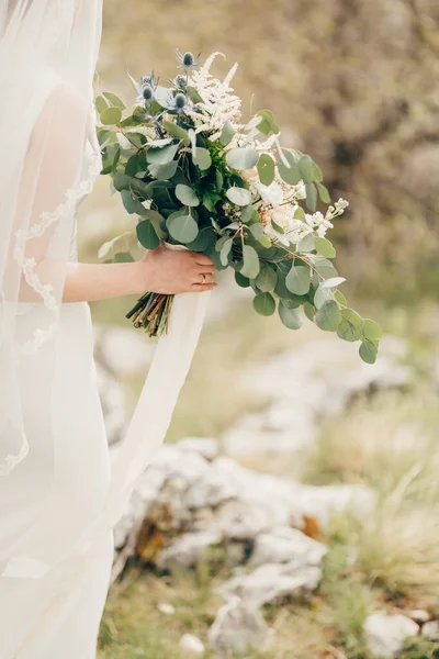 Ramo de flores en las manos de la novia en un vestido blanco con un velo. De cerca. — Foto de Stock