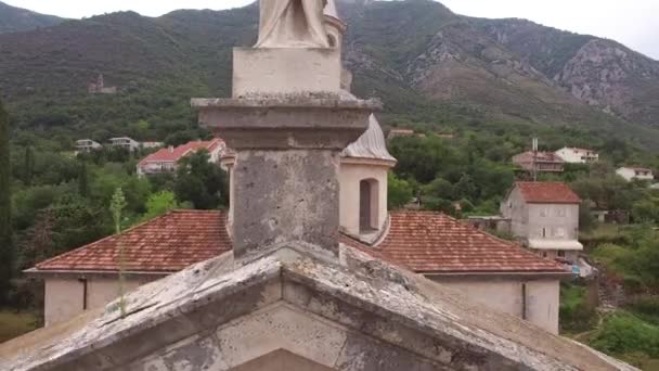 Standbeeld van de Maagd op de achtergrond van de klokkentoren van de Kerk van Onze Lieve Vrouw Geboorte in Prcanj — Stockvideo