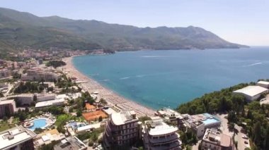 Budva sahillerindeki şemsiye ve otellerin altındaki güneş pansiyonlarının insansız hava aracı görüntüsü