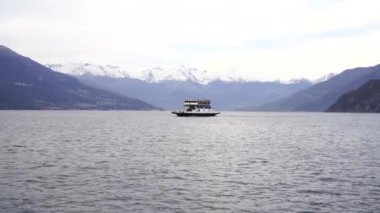 Yolcu feribotu karlı dağların arka planına karşı gölde yüzüyor. Como, İtalya