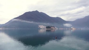 Kotor Körfezi 'ndeki adalar sisin içindeki dağların arka planına karşı. Perast, Karadağ