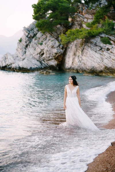Pengantin wanita bergaun putih berjalan di pantai — Stok Foto