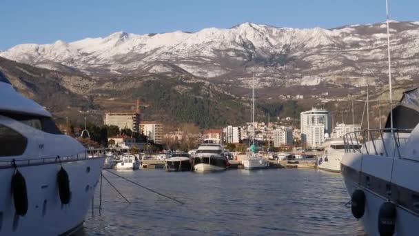 Aangemeerde jachten bij de pier in Budva tegen de achtergrond van besneeuwde bergen — Stockvideo