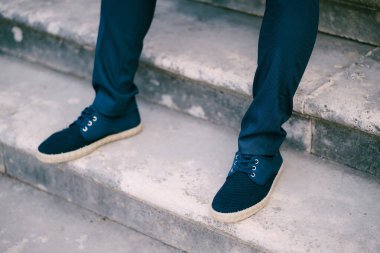Pantolonda damat ayakları ve taş basamaklarda spor ayakkabılar.