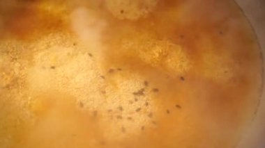 Özbek pilavı için kaynar sosla birlikte bir kazanın üzerinden buhar yükseliyor