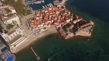 Körfezdeki eski Budva kasabasının çatıları yeşil dağların arka planına karşı.