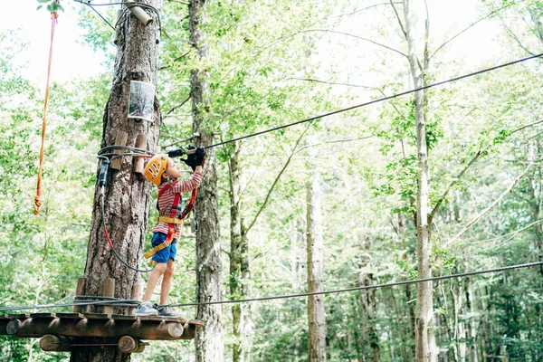Junge befestigt Gurt an Sicherheitsseil an Seilrutsche zwischen Bäumen — Stockfoto