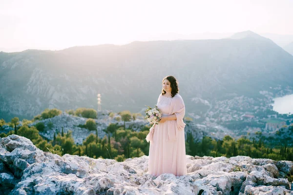 산을 배경으로 바위 위에 꽃다발이 놓여 있는 신부 — 스톡 사진
