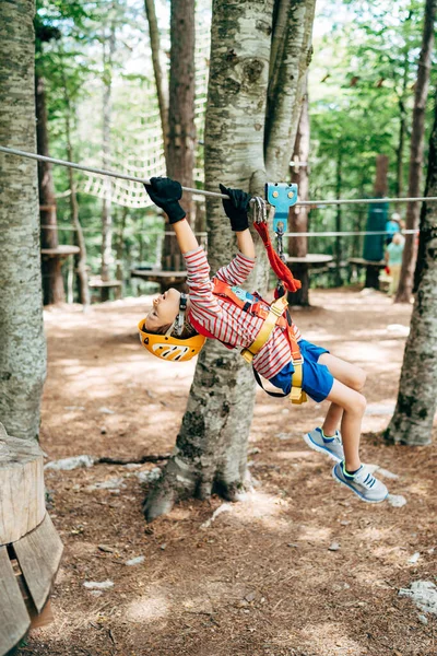 Junge klettert mit den Händen die Seilrutsche hoch und hält sich am Sicherheitsseil fest — Stockfoto