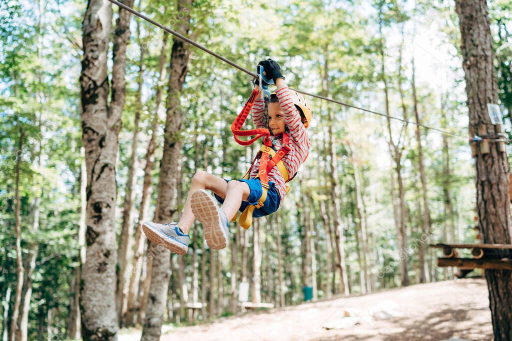 Boy goes down the zip line in the adventure park