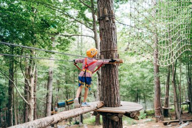 Çocuk ağaçtaki platforma giden ahşap hava yolu boyunca yürüyor.
