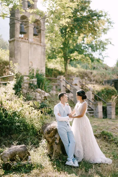 Mariée et marié assis embrassant près de l'ancien clocher près de l'église de Prcanj — Photo