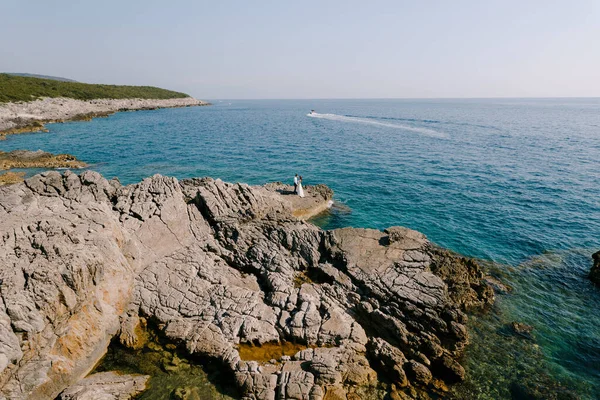 Наречений і наречений стоять на скелястій скелі біля моря — стокове фото