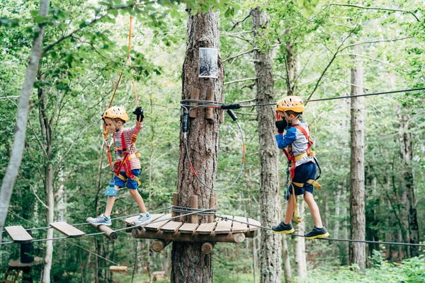 Junge läuft am Seil entlang zur Holzplattform, und der zweite geht an der Agility-Brücke entlang — Stockfoto