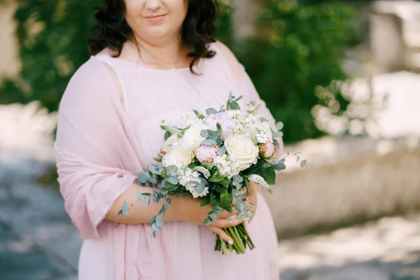 Bukett med blommor i händerna på bruden i en rosa klänning — Stockfoto