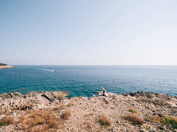 Наречена і наречена стоять на скелястому березі на тлі моря — стокове фото