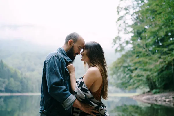 El hombre y la mujer se abrazan mientras están de pie en la orilla del lago. Primer plano —  Fotos de Stock