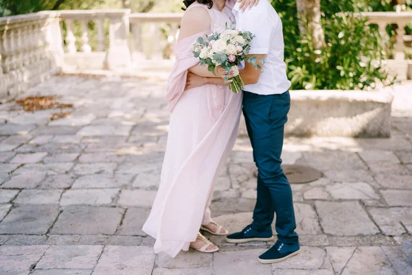 Bräutigam umarmt Braut mit Blumenstrauß — Stockfoto
