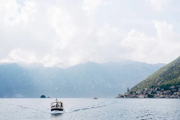 O barco a motor navega ao longo da Baía de Kotor contra o pano de fundo da cidade de Perast. Montenegro — Fotografia de Stock