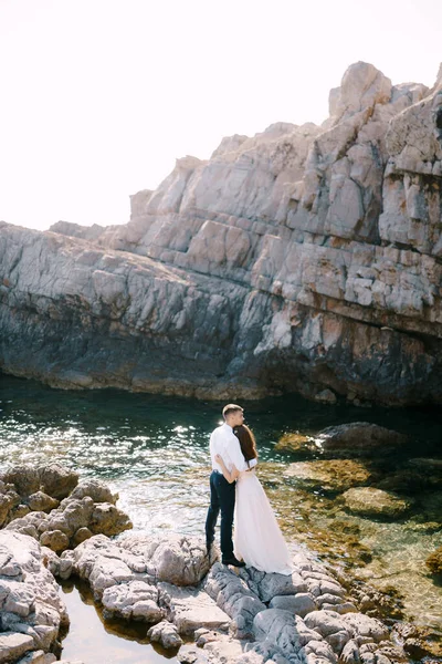 Groom étreint mariée tout en se tenant sur les pierres. Vue arrière — Photo