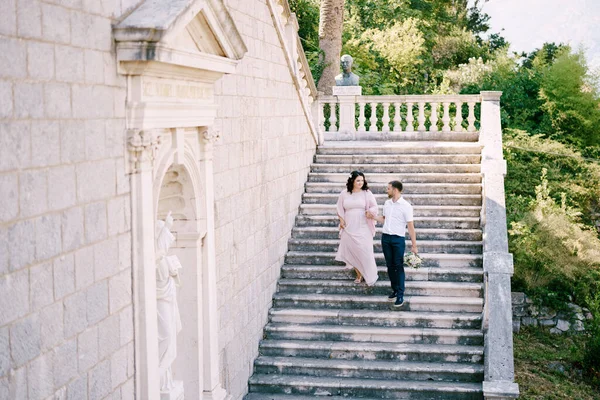 Menyasszony és vőlegény le a lépcsőn egy gyönyörű villa egy zöld kertben — Stock Fotó