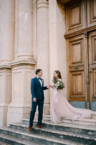 Наречений і наречений стоять на кам'яних сходах стародавньої церкви біля дверей — стокове фото