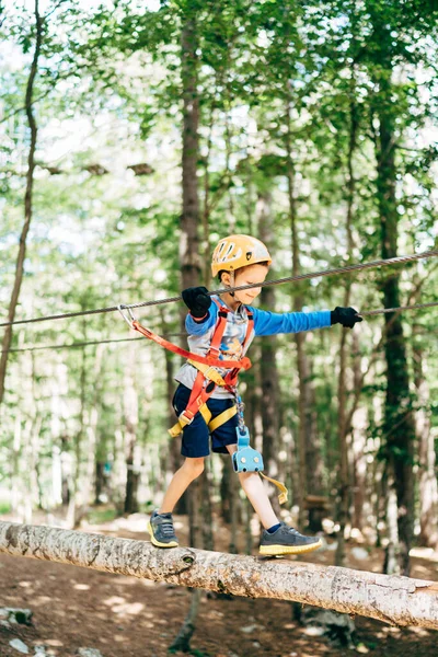 Junge mit Helm wandert auf dem hölzernen Höhenweg im Erlebnispark — Stockfoto