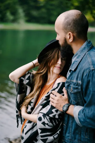 De man knuffelt de schouders van een zwangere vrouw bij het meer. Portret — Stockfoto