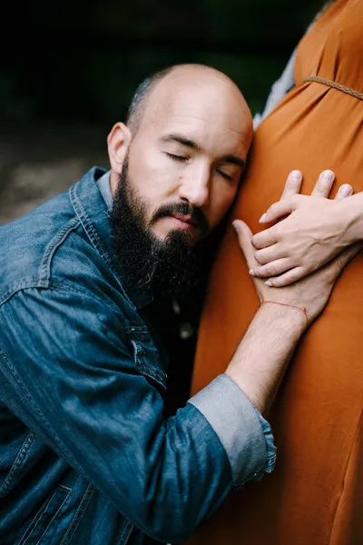 Hombre abraza a mujer vientre embarazada, apoyando su oreja contra ella —  Fotos de Stock