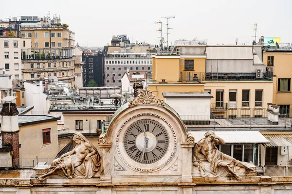 Alte Uhr auf dem Dach des Hauses mit Statuen an den Seiten. Mailand, Italien — Stockfoto