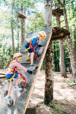Çocuklar karabinalarını yeniden düzenleyerek tırmanırlar.