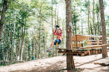 Çocuk ipten aşağı iniyor. Elleriyle sigortaya tutunuyor.