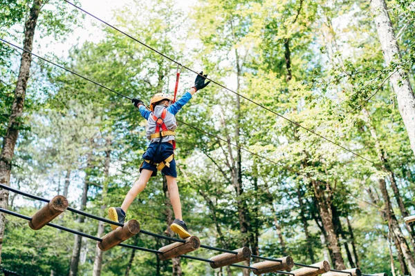 Çocuk çeviklik köprüsünde yürüyor İplere tutunarak
