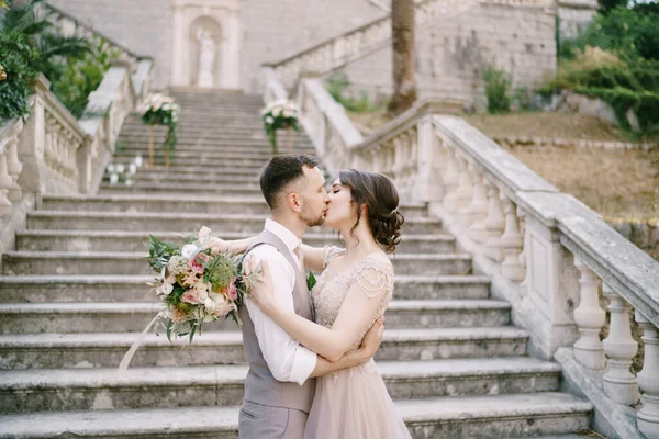 Braut küsst Bräutigam auf der Steintreppe neben der alten Villa — Stockfoto