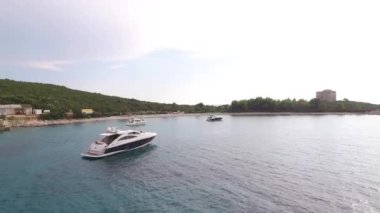 Yatlar, yeşil dağların arka planına karşı denizde duruyor.