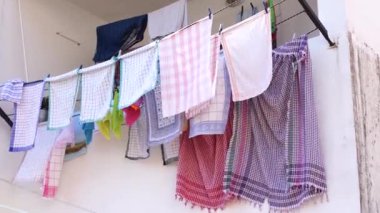 Rüzgarda dalgalanan renkli havlular bir iple balkonda.