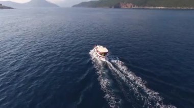 Gemi denizde yelken açar, dağların arkasından bakar.