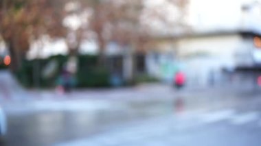 Arabalar caddeden aşağı iniyor ve yayalar kaldırım boyunca yürüyor. Bulanık