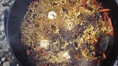 Sarımsak başlıklı Özbek pilavı bir kazanda pişiyor