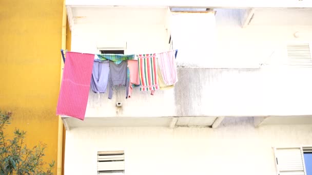 Colorida lavandería revoloteando en el viento en el balcón con cuerdas — Vídeo de stock