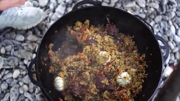 Usbekisches Pilaf mit einem Schlitzlöffel auf einen Teller gießen — Stockvideo